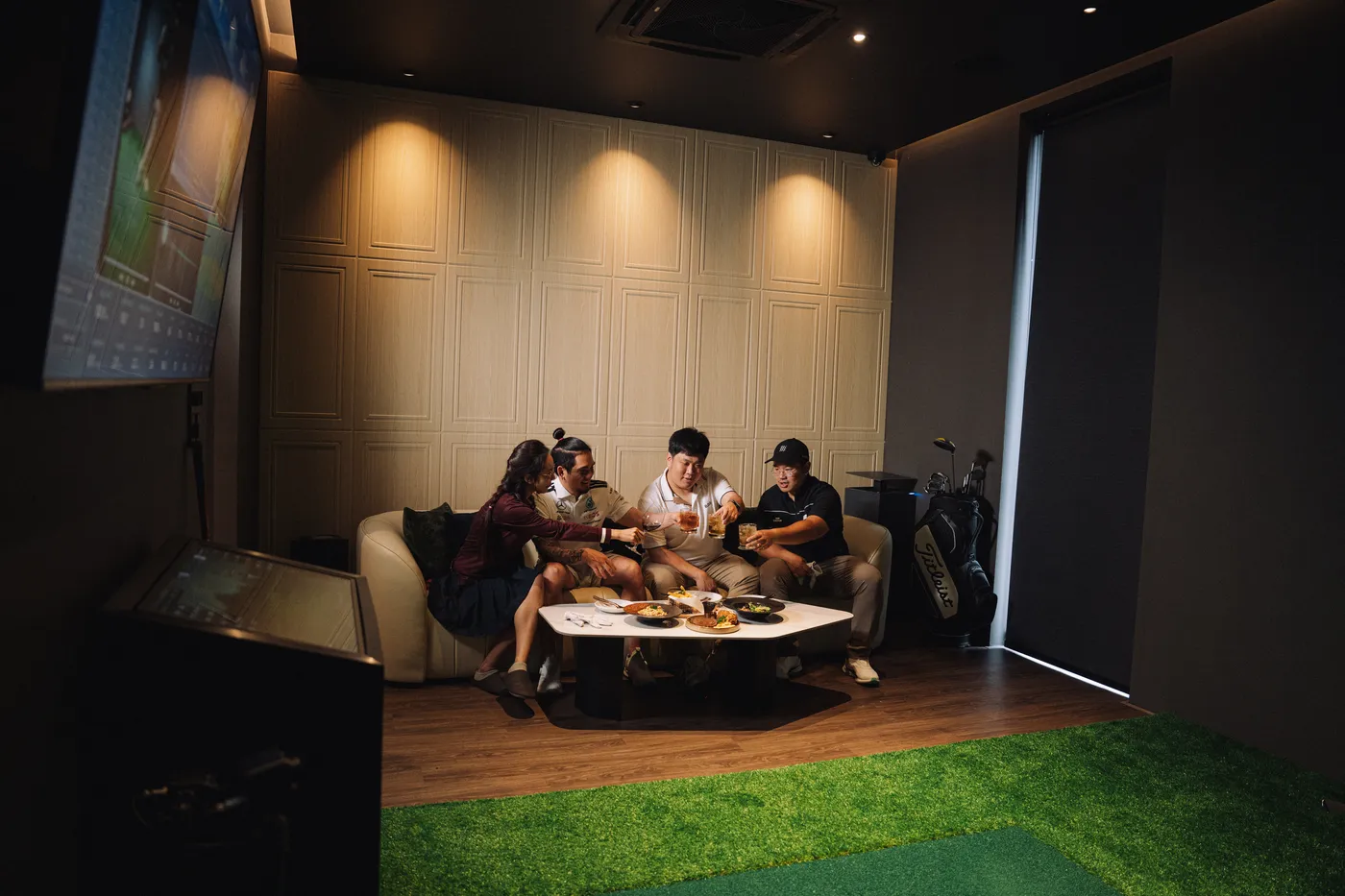กลุ่มเพื่อนสี่คนนั่งชนแก้วพร้อมอาหารบนโซฟาในห้องส่วนตัวของ 4th Swing Club