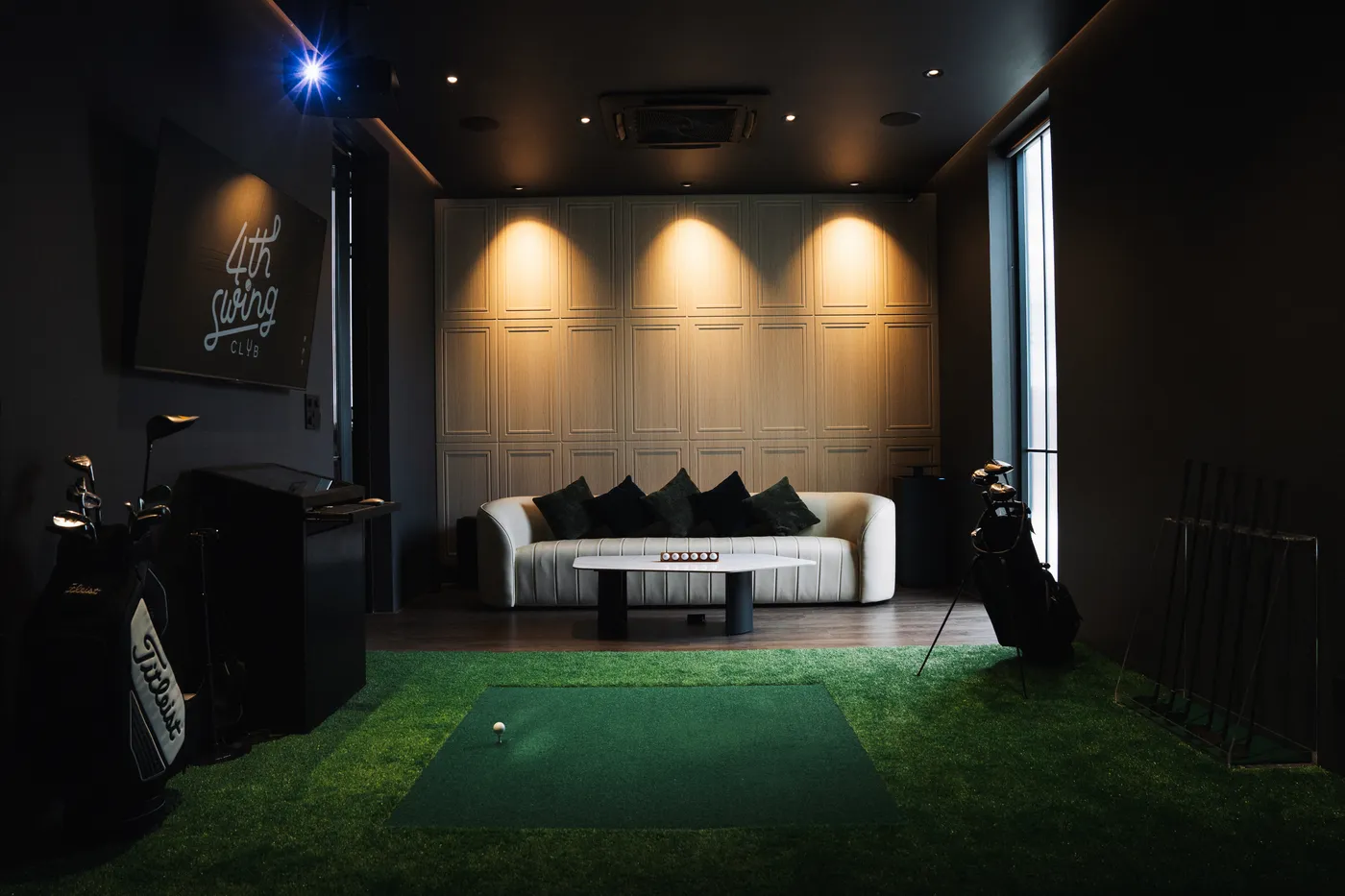 ห้องส่วนตัวของ 4th Swing Club มีโซฟาหนัง โต๊ะกลาง พื้นหญ้าเทียม และจอทีวีแสดงโลโก้ 4th Swing Club